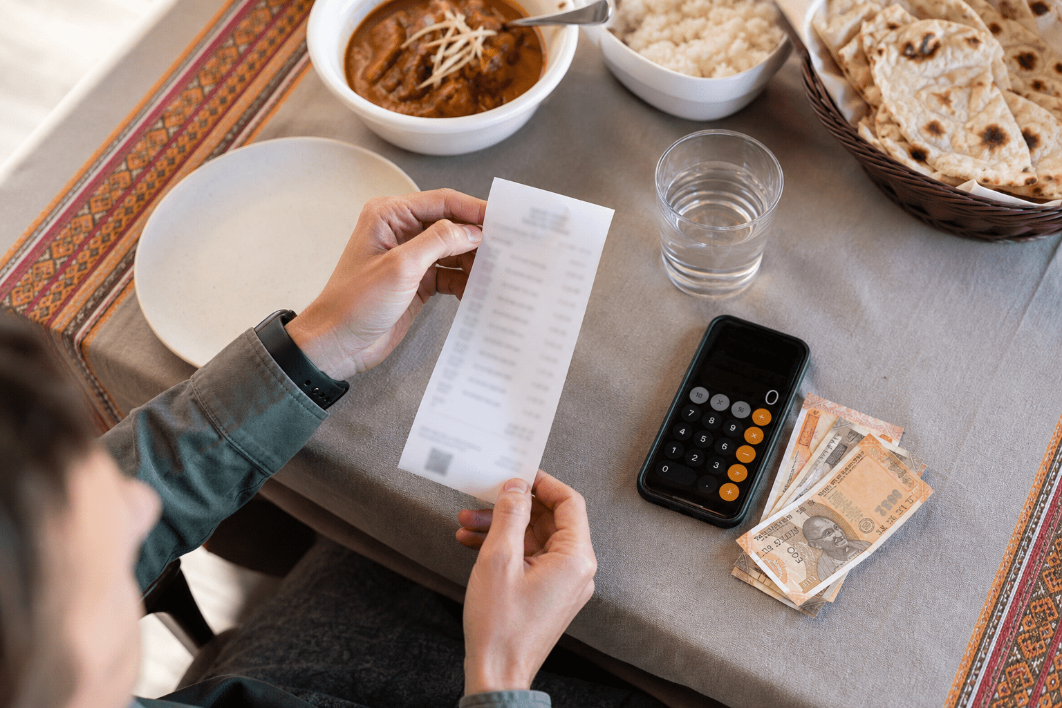 Tipping in India: Etiquette, Suggested Amounts, and Service Charges (2026 Guide) 5 Traveler checking an Indian restaurant bill before leaving a tip